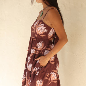 woman wearing a brown colored mini dress with tie back detail and protea print