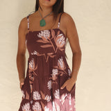 woman wearing a brown colored mini dress with tie back detail and protea print