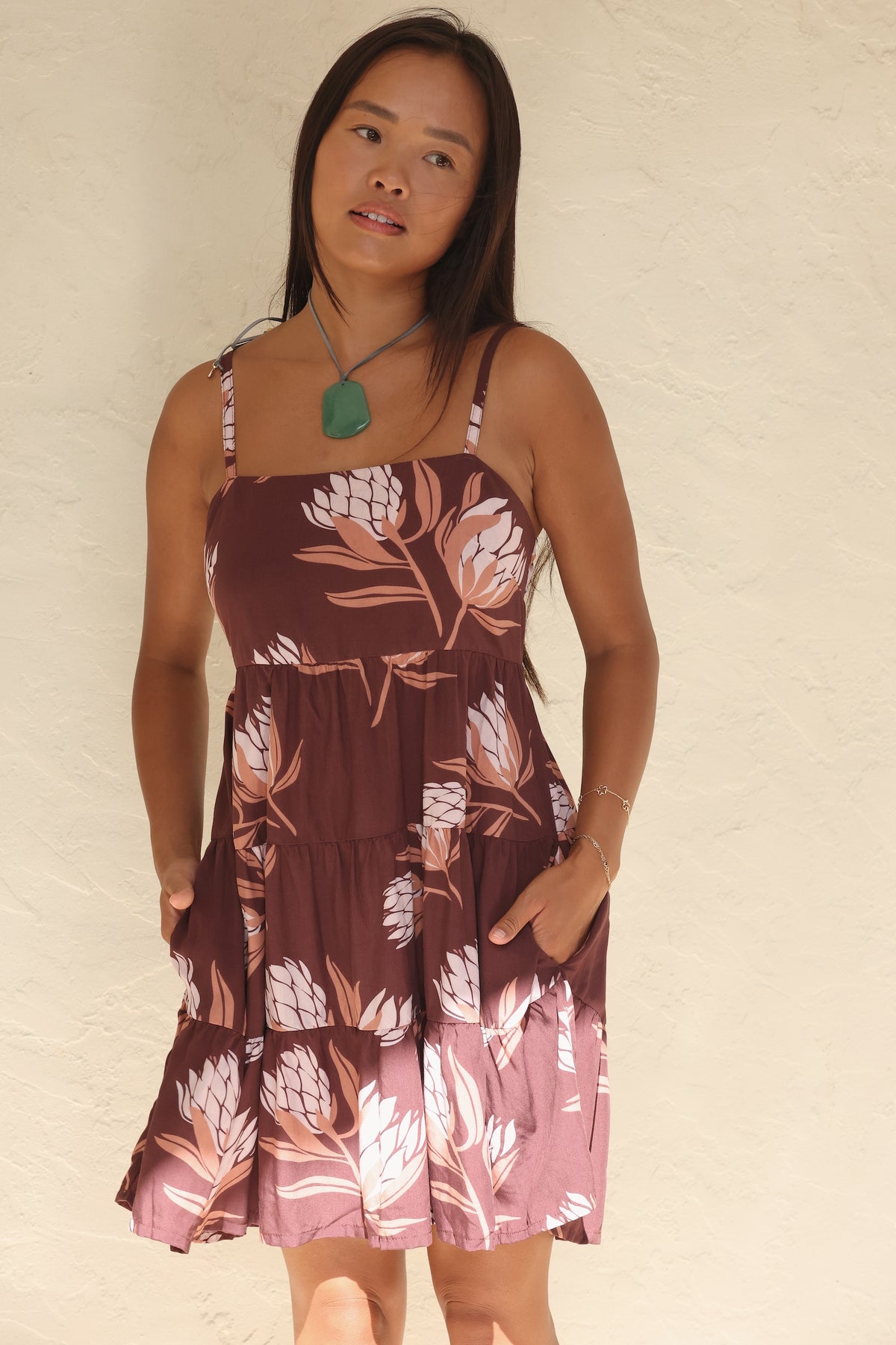woman wearing a brown colored mini dress with tie back detail and protea print