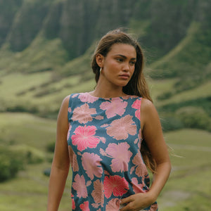 woman with brown hair wearing a navy high neck sleeveless top with bright pink hibiscus print