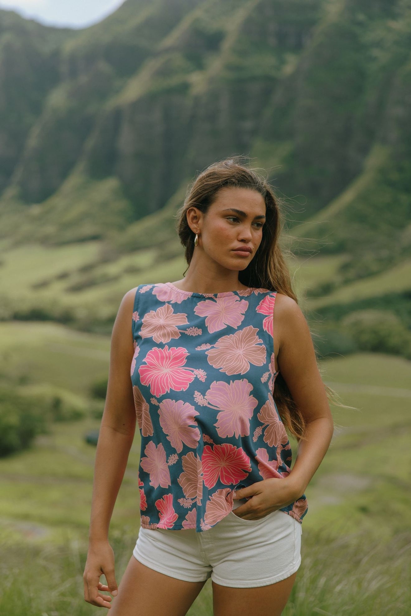 woman with brown hair wearing a navy high neck sleeveless top with bright pink hibiscus print