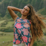 woman with brown hair wearing a navy high neck sleeveless top with bright pink hibiscus print