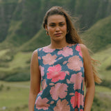 woman with brown hair wearing a navy high neck sleeveless top with bright pink hibiscus print