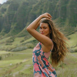 woman with brown hair wearing a navy high neck sleeveless top with bright pink hibiscus print