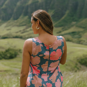 woman with brown hair wearing a navy high neck sleeveless top with bright pink hibiscus print