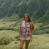 woman with brown hair wearing a navy high neck sleeveless top with bright pink hibiscus print