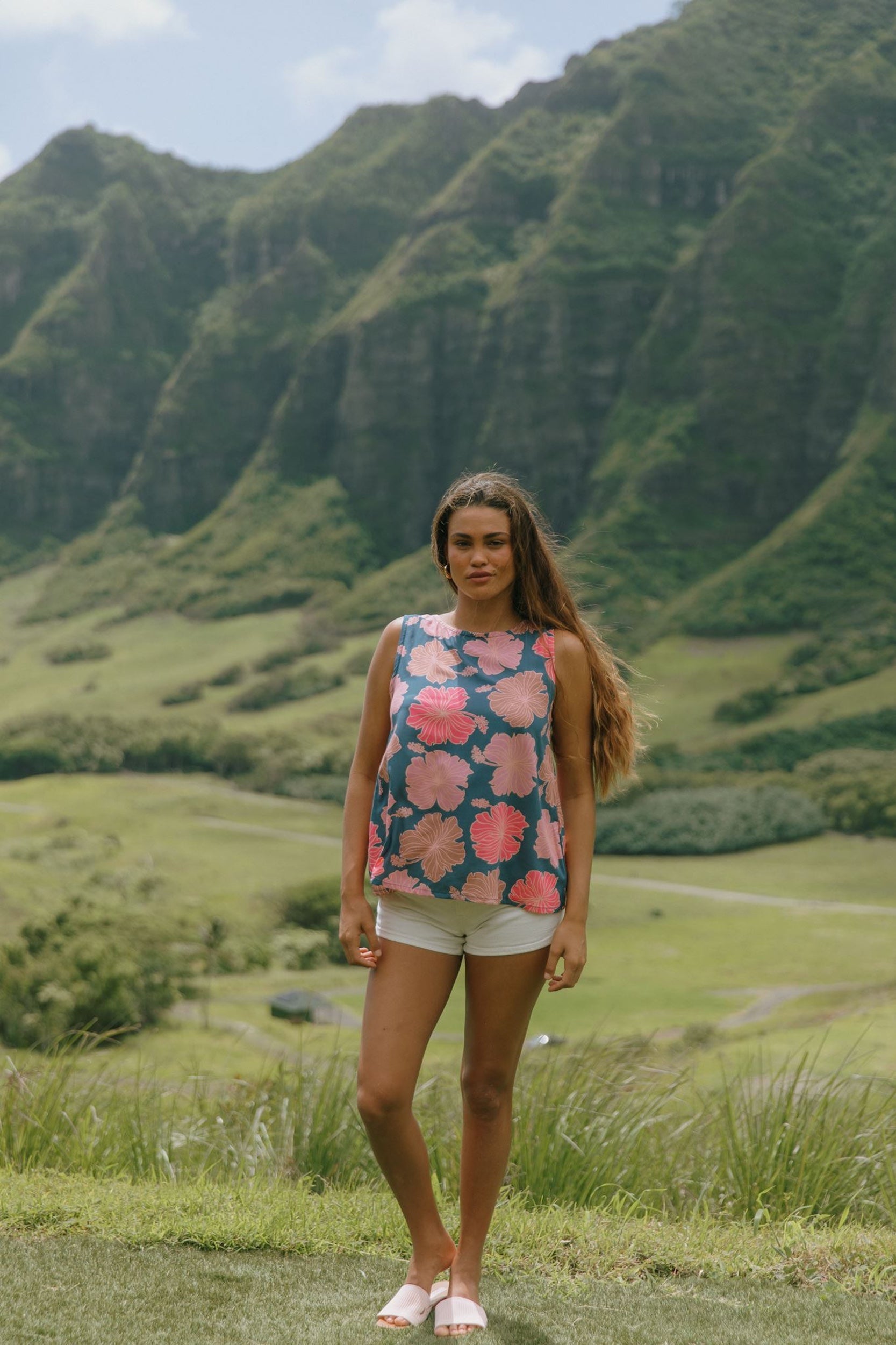 woman with brown hair wearing a navy high neck sleeveless top with bright pink hibiscus print
