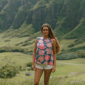 woman with brown hair wearing a navy high neck sleeveless top with bright pink hibiscus print
