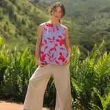 woman with brown hair wearing a sleeveless blouse with periwinkle background and bright red hibiscus print.