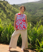 woman with brown hair wearing a sleeveless blouse with periwinkle background and bright red hibiscus print.