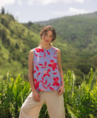 woman with brown hair wearing a sleeveless blouse with periwinkle background and bright red hibiscus print.