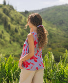 woman with brown hair wearing a scrunchie with periwinkle background and bright red hibiscus print.