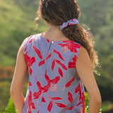 woman with brown hair wearing a scrunchie with periwinkle background and bright red hibiscus print.