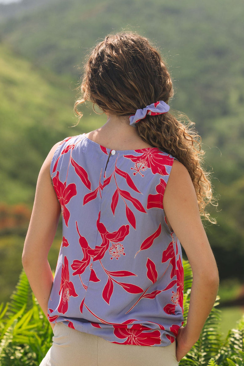 woman with brown hair wearing a scrunchie with periwinkle background and bright red hibiscus print.