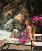 woman with brown hair wearing a sleeveless blouse with periwinkle background and bright red hibiscus print.
