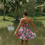 woman with brown hair wearing a navy strapless mini dress with ruffle hem and bright pink hibiscus print