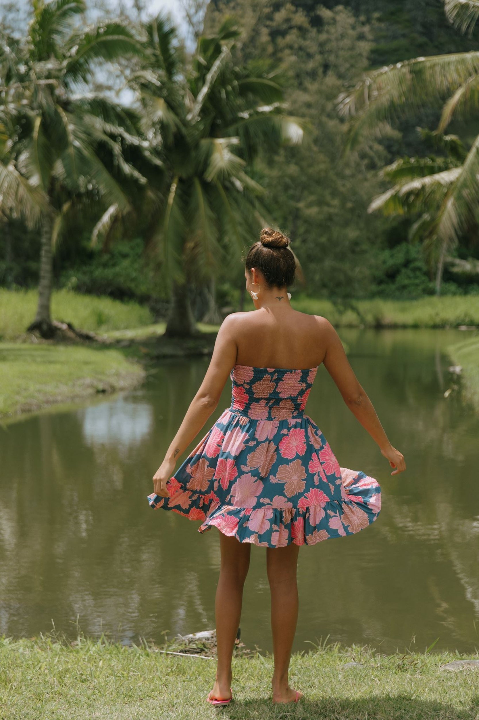 woman with brown hair wearing a navy strapless mini dress with ruffle hem and bright pink hibiscus print