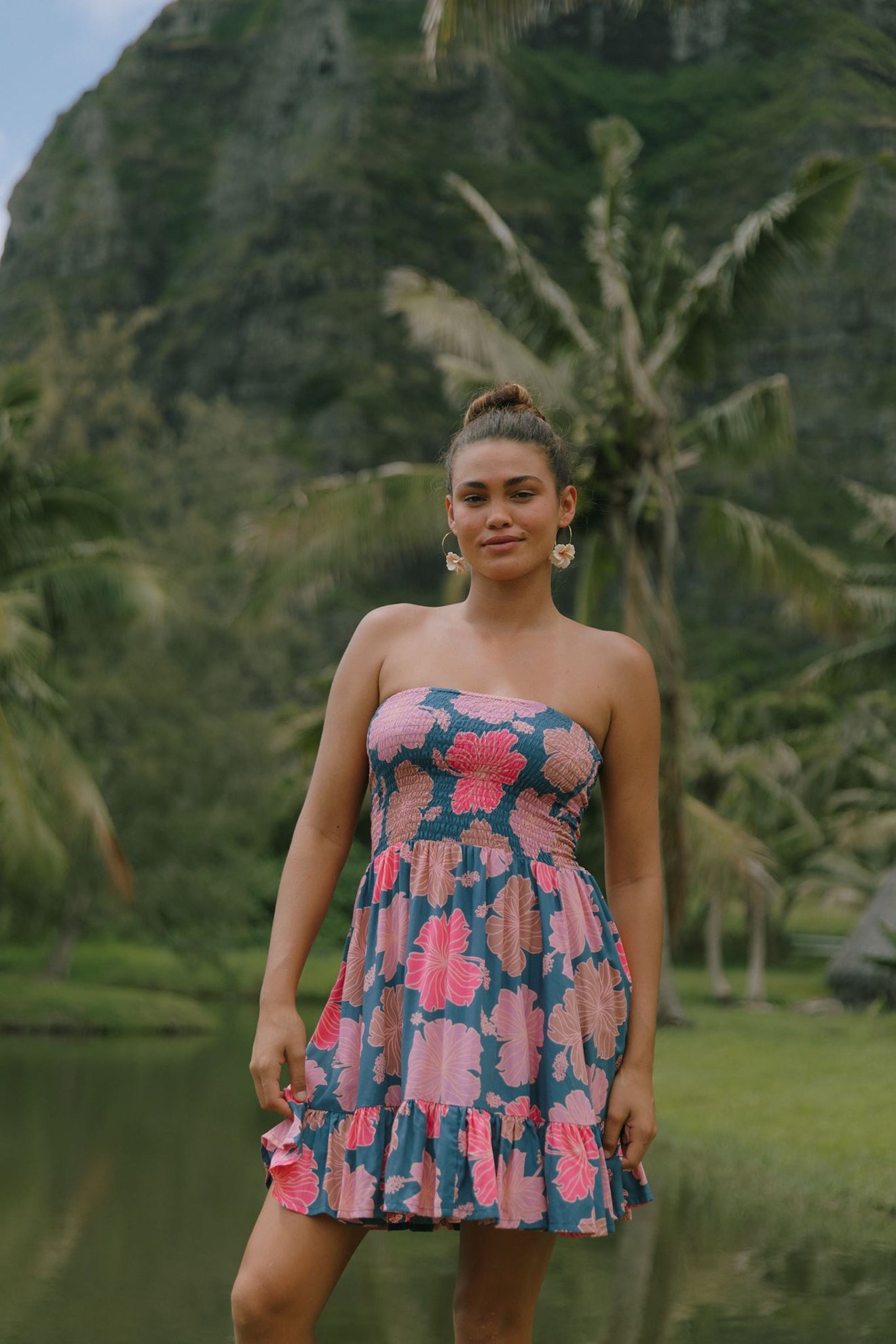 woman with brown hair wearing a navy strapless mini dress with ruffle hem and bright pink hibiscus print