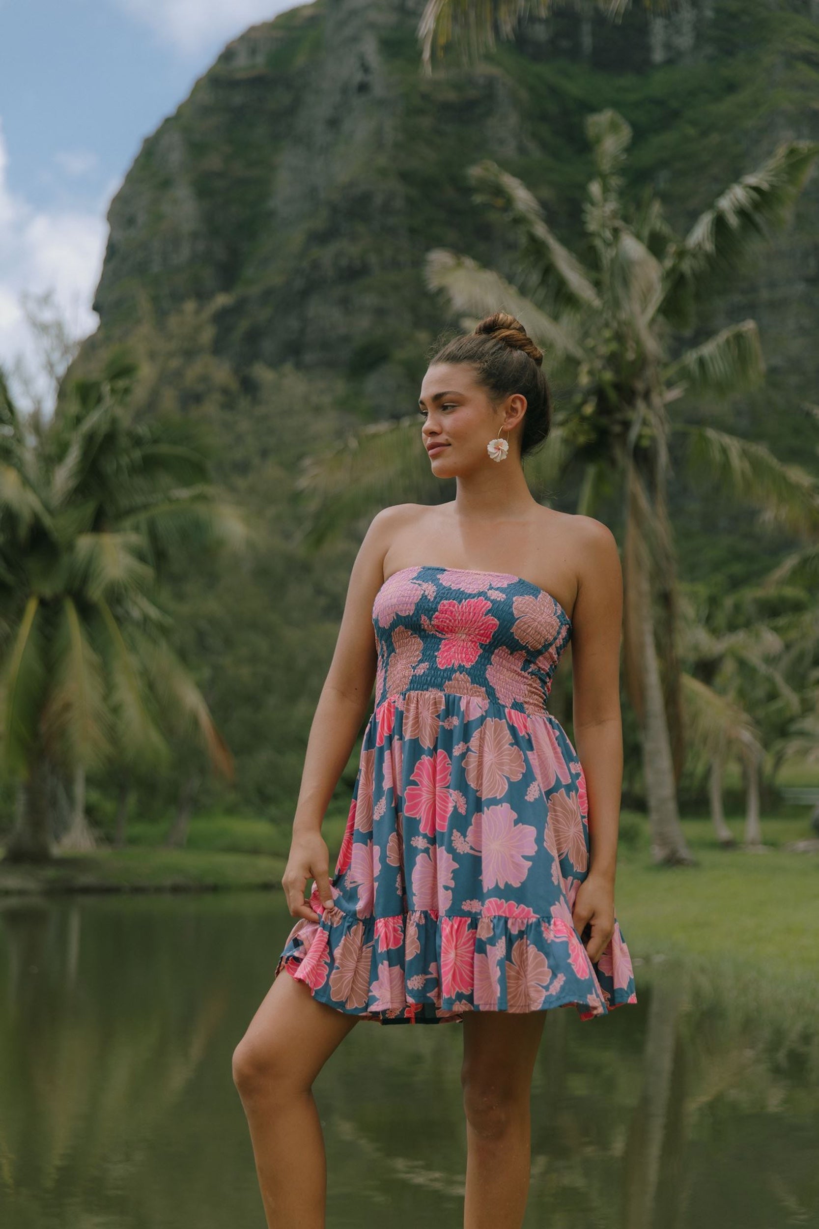 woman with brown hair wearing a navy strapless mini dress with ruffle hem and bright pink hibiscus print