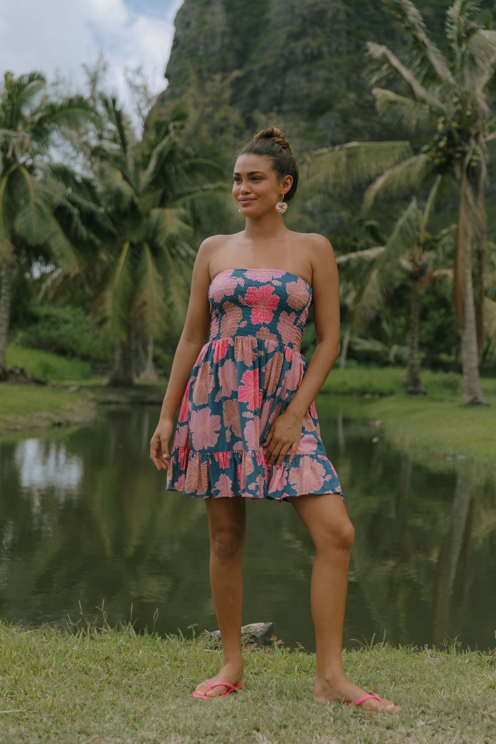 woman with brown hair wearing a navy strapless mini dress with ruffle hem and bright pink hibiscus print
