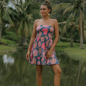woman with brown hair wearing a navy strapless mini dress with ruffle hem and bright pink hibiscus print
