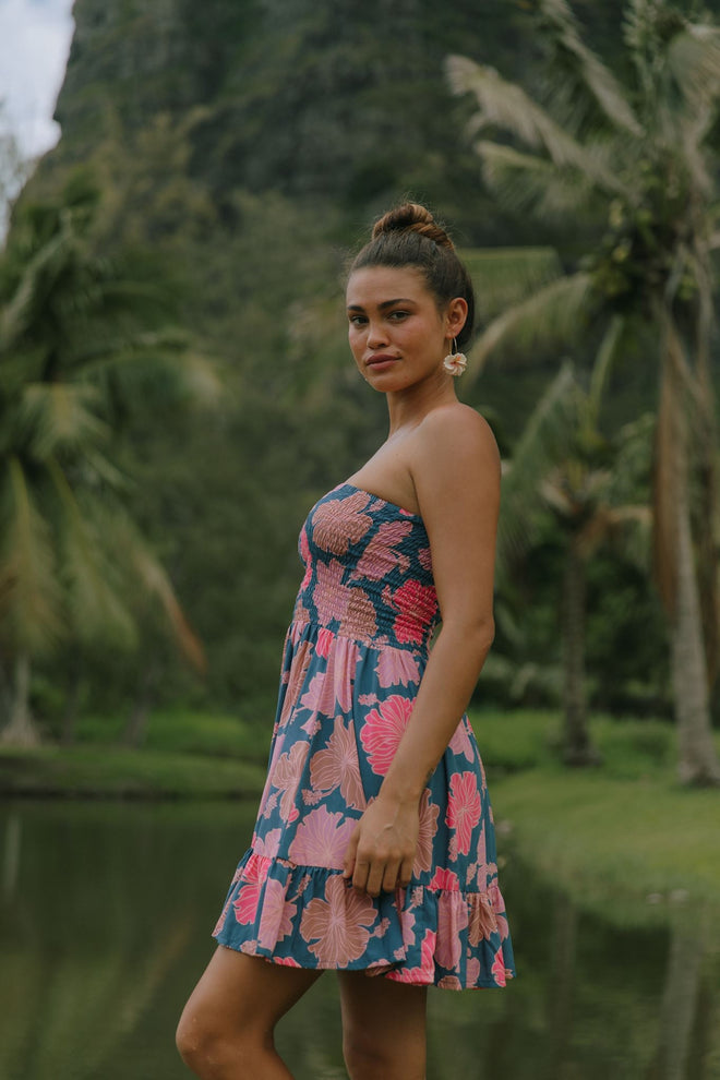 woman with brown hair wearing a navy strapless mini dress with ruffle hem and bright pink hibiscus print