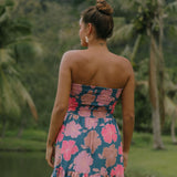 woman with brown hair wearing a navy strapless mini dress with ruffle hem and bright pink hibiscus print