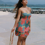 woman with brow hair wearing a strapless minidress with orange and yellow lei pua print