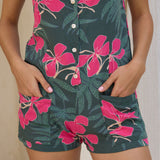 woman with brown hair wearing dark green tie back romper with fern and ginger print