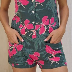 woman with brown hair wearing dark green tie back romper with fern and ginger print