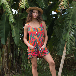 woman with brown hair wearing a colorful romper with tropical lei print