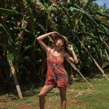 woman with brown hair wearing a colorful romper with tropical lei print