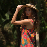 woman with brown hair wearing a colorful romper with tropical lei print