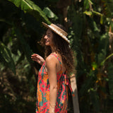 woman with brown hair wearing a colorful romper with tropical lei print