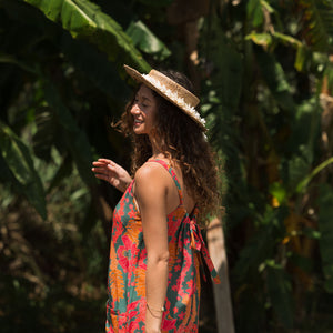 woman with brown hair wearing a colorful romper with tropical lei print