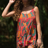 woman with brown hair wearing a colorful romper with tropical lei print
