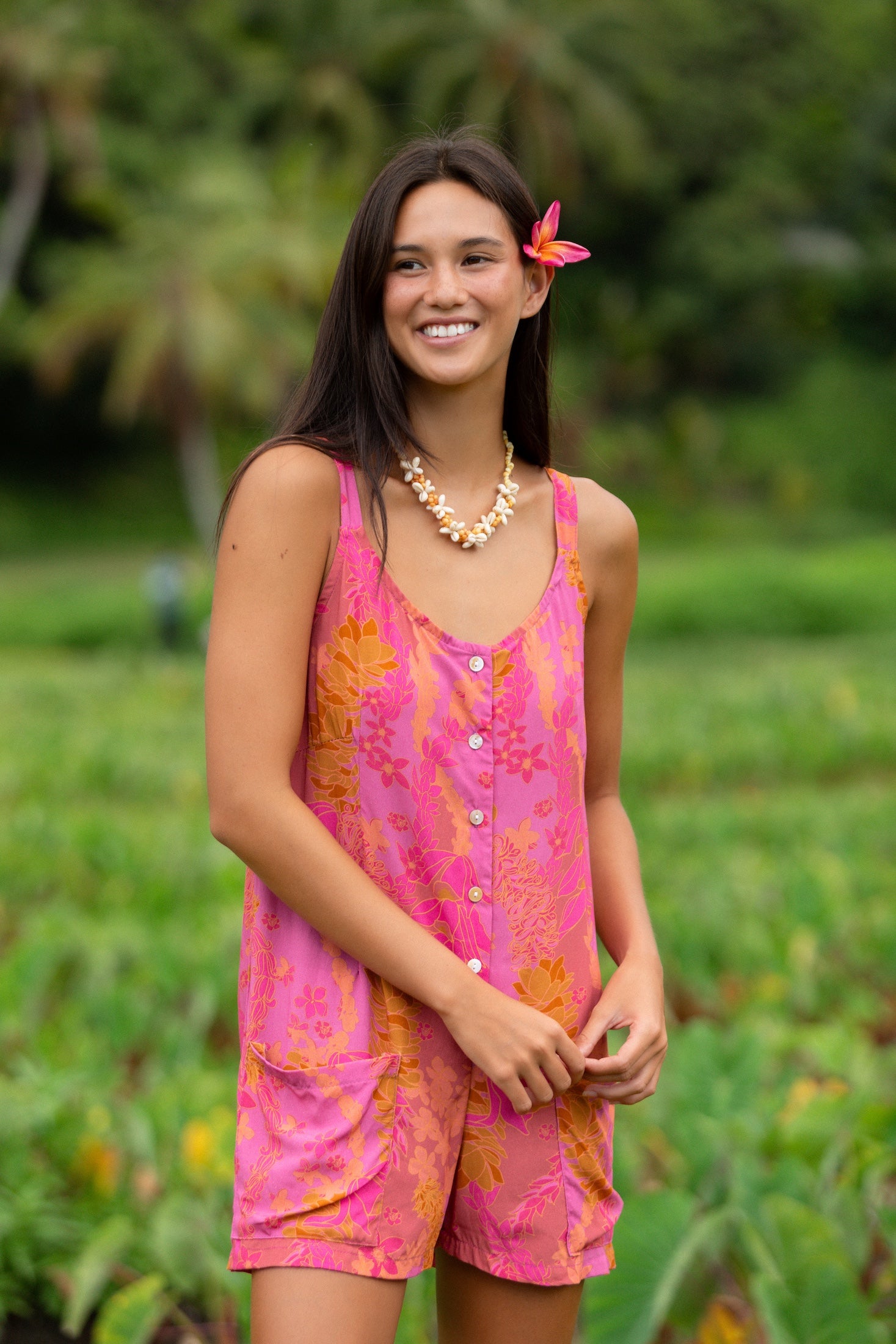 woman wearing a pink tie back romper with lei print