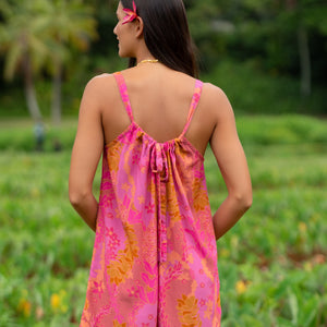 woman wearing a pink tie back romper with lei print