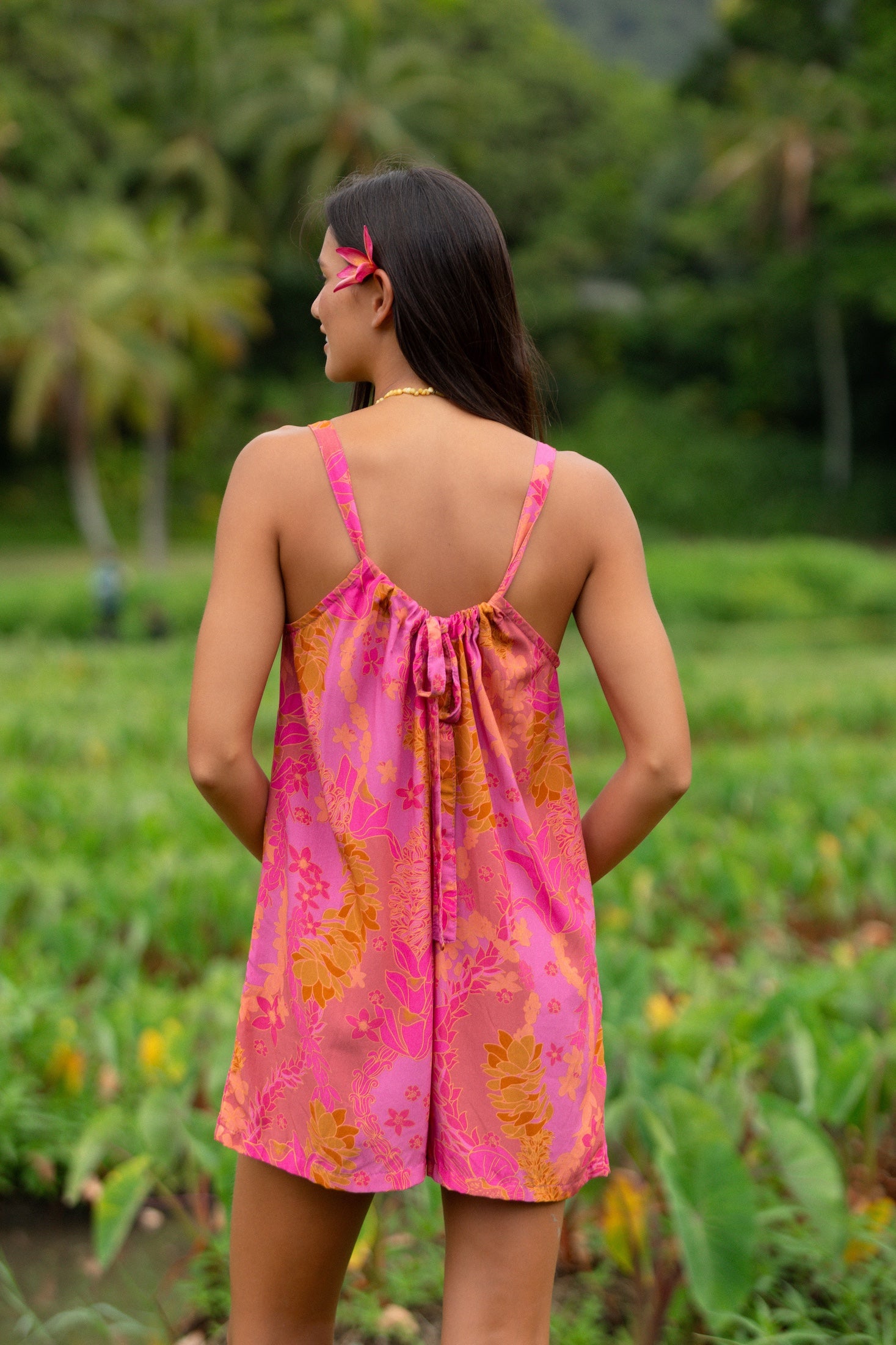 woman wearing a pink tie back romper with lei print