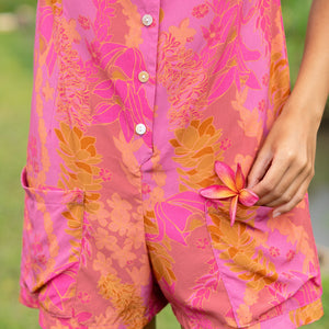woman wearing a pink tie back romper with lei print