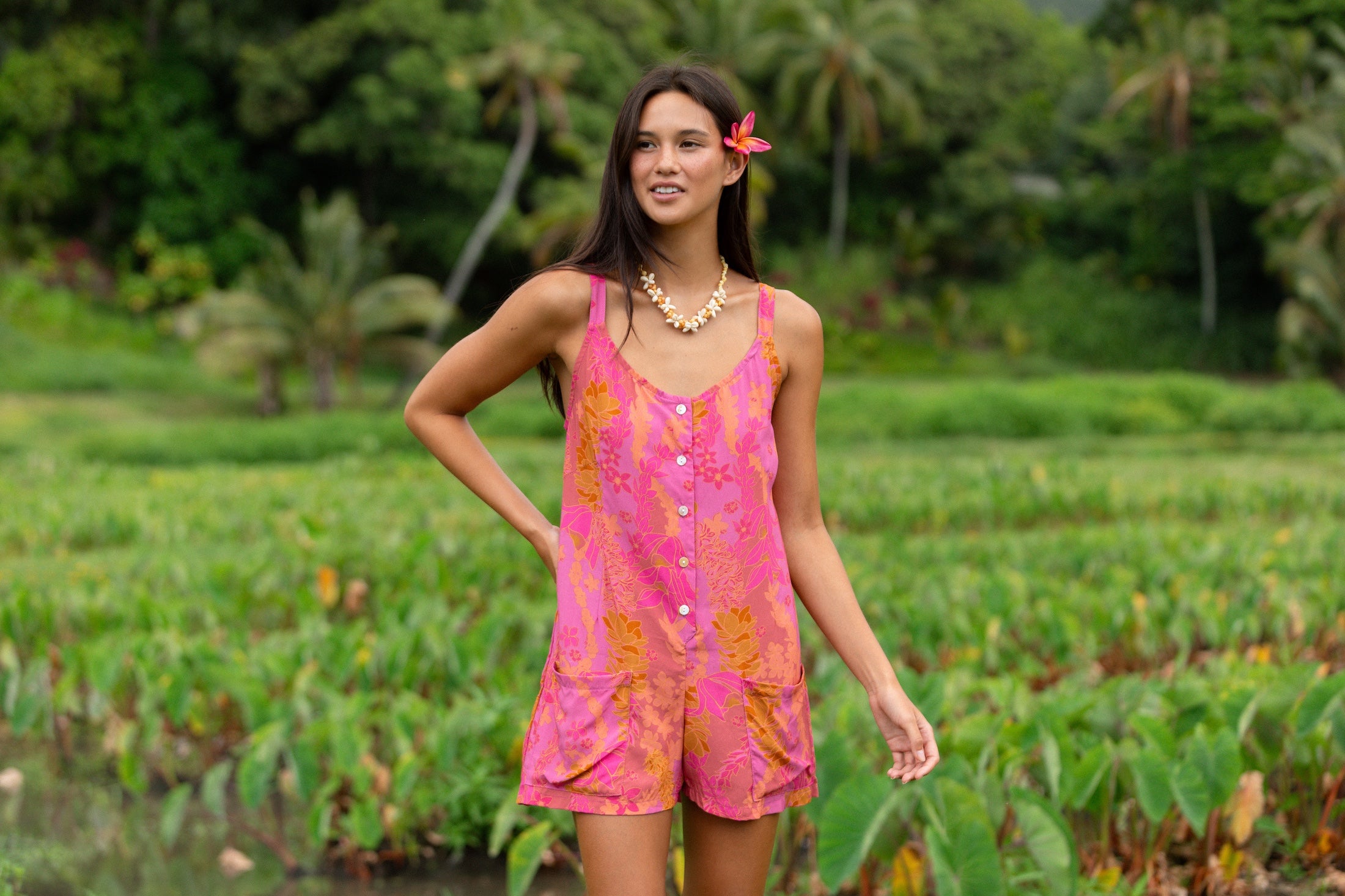 woman wearing a pink tie back romper with lei print
