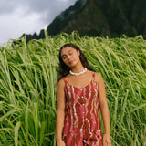 woman with brown hair wearing a red-brown colored romper with buttons, a tie back, front pockets, and lei print