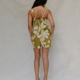 woman with brown hair wearing a green tie back romper with naupaka print
