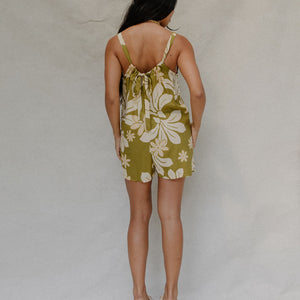 woman with brown hair wearing a green tie back romper with naupaka print