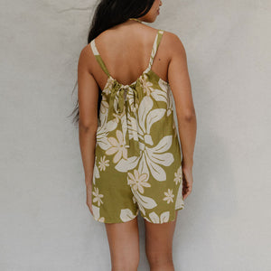 woman with brown hair wearing a green tie back romper with naupaka print