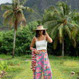 woman with brown hair wearing teal flowy pants with orange and pink foral print
