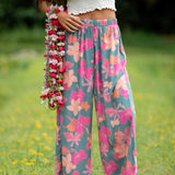 woman with brown hair wearing teal flowy pants with orange and pink foral print