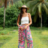 woman with brown hair wearing teal flowy pants with orange and pink foral print