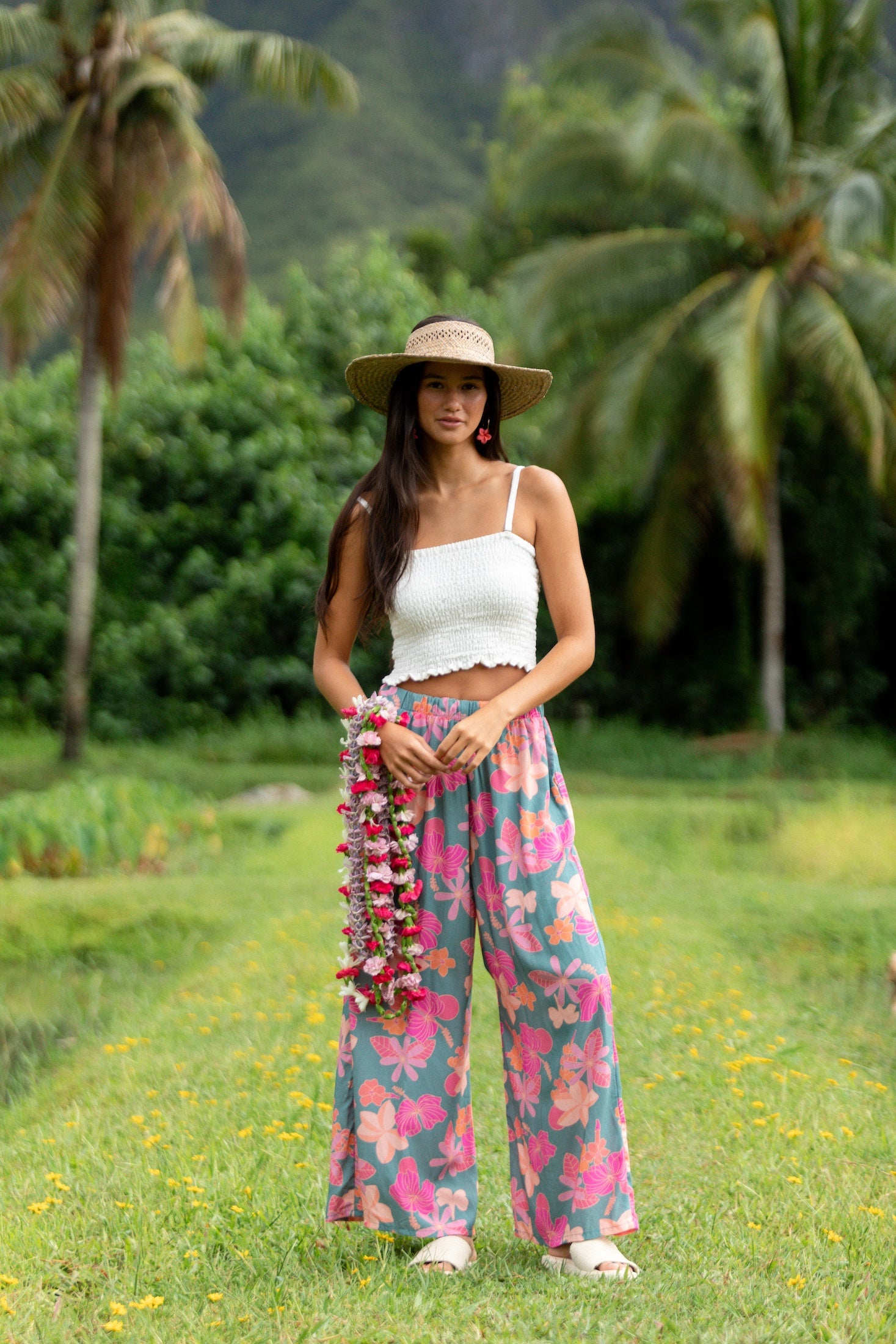 woman with brown hair wearing teal flowy pants with orange and pink foral print