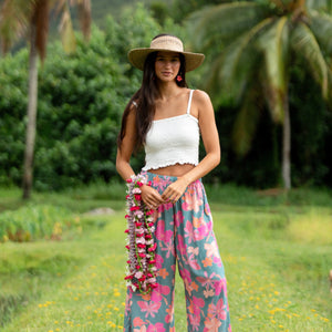woman with brown hair wearing teal flowy pants with orange and pink foral print